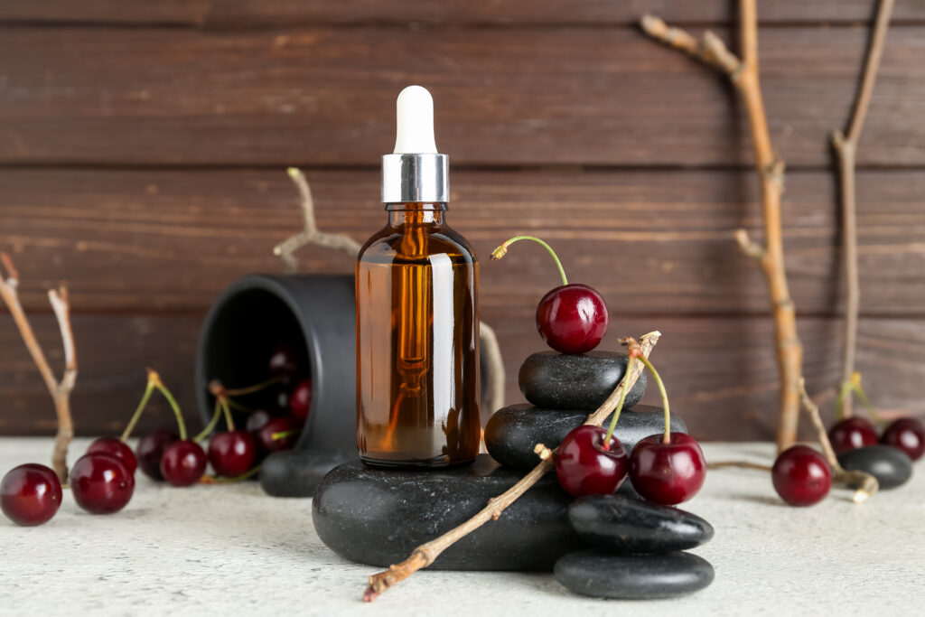 Gros plan sur un flacon d'huile de noyau de cerise, entourée de cerises