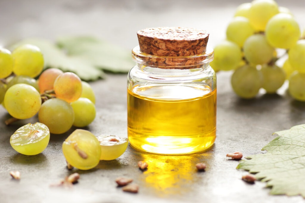 Fiole d'huile de raisin avec des raisins autour