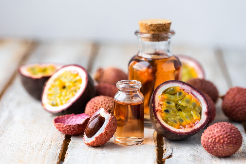 Gros plan sur des fruits de la passion coupés en deux avec deux fioles d'huile de fruit de la passion