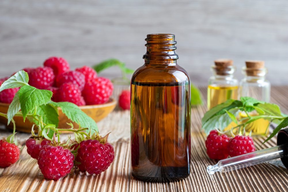Fiole de pépins de framboise avec des framboises autour