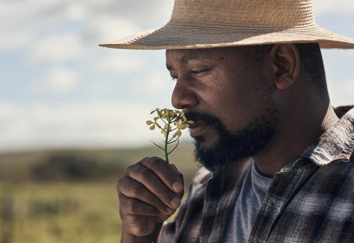 Sourcing éthique illustré par le portrait photo d'un homme avec une fleur dont il respire le parfum